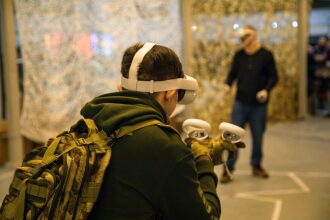 Игрок в VR-гарнитуре LASERWAR с контроллерами готовится к виртуальному сражению.