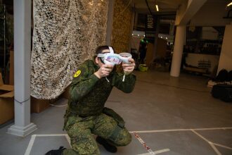 Боец в камуфляже исследует виртуальный мир с VR-контроллерами.