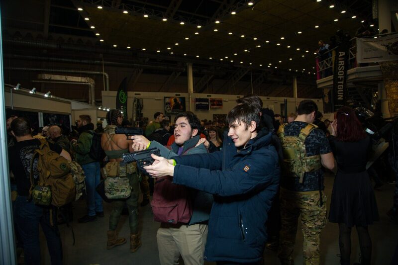 Двое парней пробуют лазертаг-оружие LASERWAR на выставке.