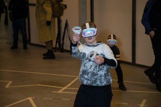 Мальчик в VR-гарнитуре LASERWAR активно управляет игрой.