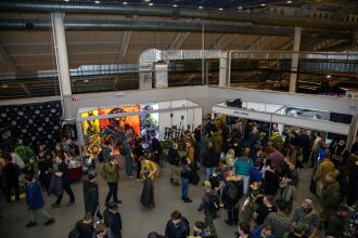 Люди осматривают стенды с яркими изображениями бойцов LASERWAR.