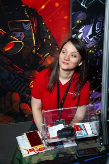 Девушка в красной футболке LASERWAR у витрины с аксессуарами.