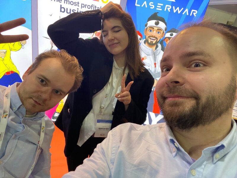 Команда LASERWAR позирует на фоне баннера.