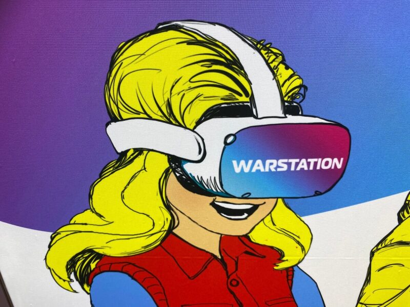 Девушка в VR-очках с надписью WARSTATION.