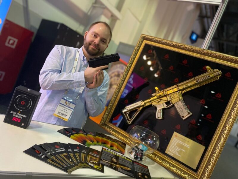 Мужчина держит бластер LASERWAR у выставочного стенда.