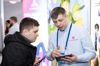 Мужчины рассматривают планшет на стенде LASERWAR.