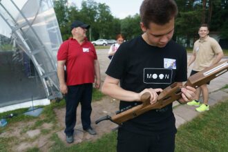 Молодой человек изучает деревянный бластер LASERWAR