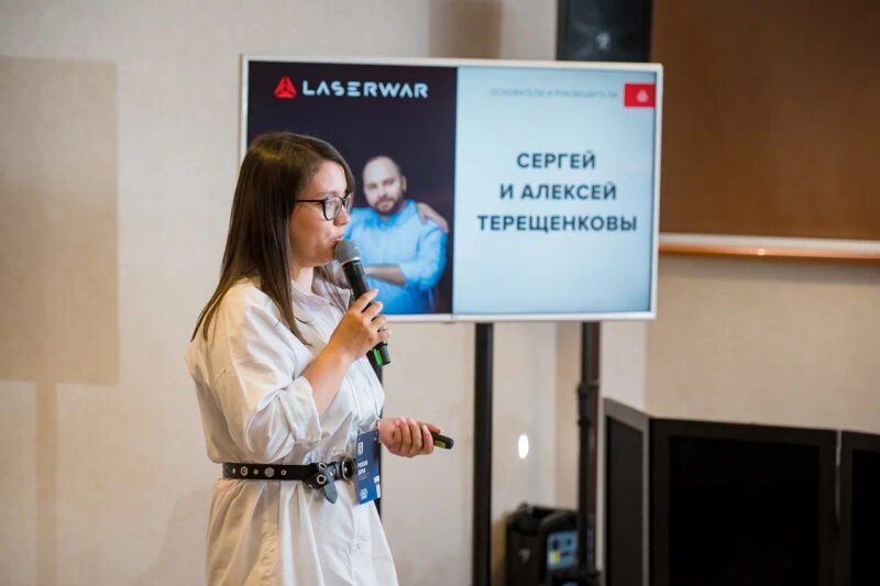 Спикер LASERWAR держит микрофон и указку