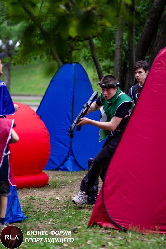 Игрок в зеленом жилете с винтовкой LASERWAR готовится к бою.
