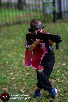 Мальчик в красном плаще целится из оружия LASERWAR.