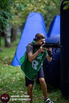 Юный боец LASERWAR в зеленом жилете прицеливается.