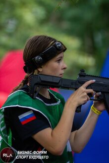 Девушка в зеленом жилете LASERWAR с винтовкой у цели.