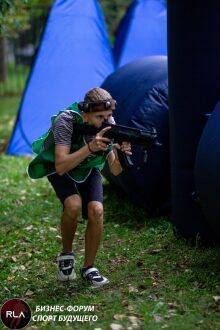 Юный стрелок LASERWAR в зелёном жилете наводит оружие.