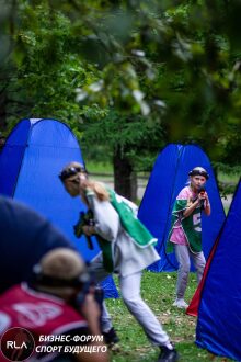 Девочка в зеленом жилете LASERWAR целится из винтовки.