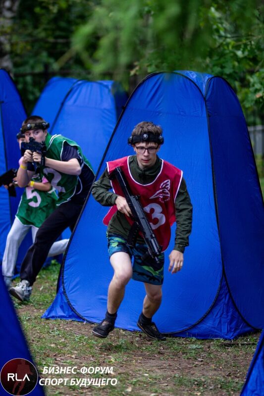Юный игрок LASERWAR в красном жилете с винтовкой в движении.