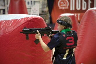 Девочка в жилете LASERWAR целится из оружия