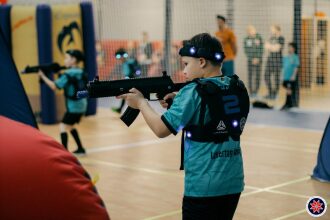 Юный боец LASERWAR прицеливается из футуристического оружия.