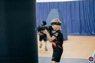 Юный боец LASERWAR целится из автомата за укрытием.