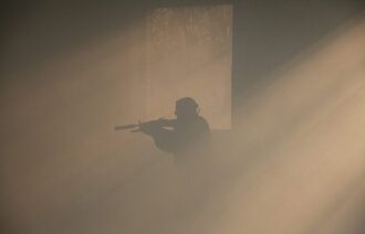Силуэт бойца LASERWAR в дыму у окна.