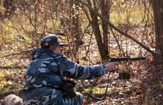 Боец LASERWAR прицеливается в осеннем лесу.