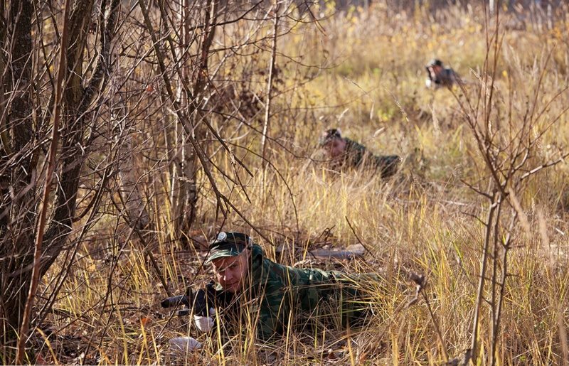 Боец LASERWAR в засаде среди осенней травы.