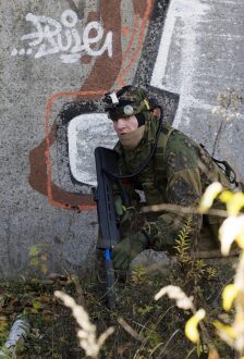 Боец LASERWAR в засаде у стены с граффити.