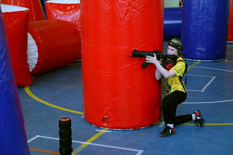 Игрок LASERWAR в желтой футболке за красным укрытием.