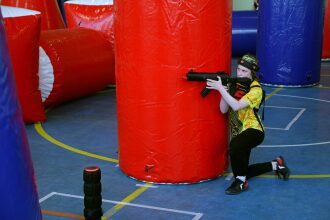 Игрок LASERWAR в желтой футболке за красным укрытием.