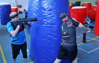 Игрок LASERWAR ведет огонь из-за синего укрытия.