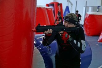 Игрок LASERWAR в камуфляже целится из автомата.