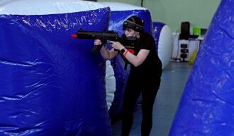 Девушка в черном с автоматом LASERWAR за синим укрытием