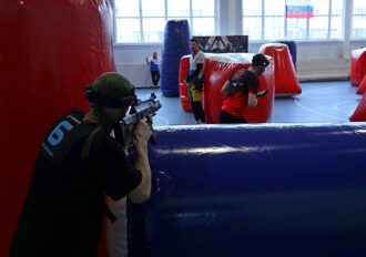 Игрок LASERWAR в черной форме занимает позицию за укрытием.