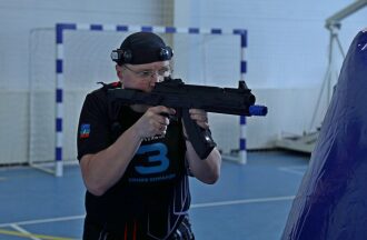 Игрок в черной форме с автоматом LASERWAR готов к выстрелу.