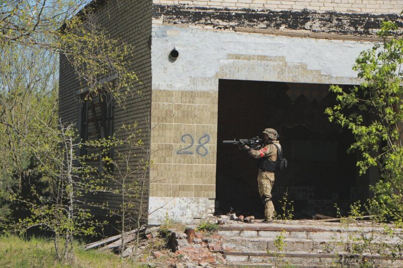 Игрок LASERWAR занимает позицию у входа в здание.
