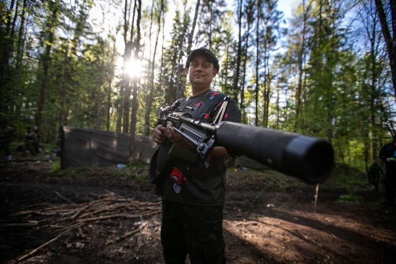 Игрок LASERWAR держит крупнокалиберную винтовку в лесу