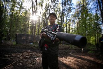 Игрок LASERWAR держит крупнокалиберную винтовку в лесу