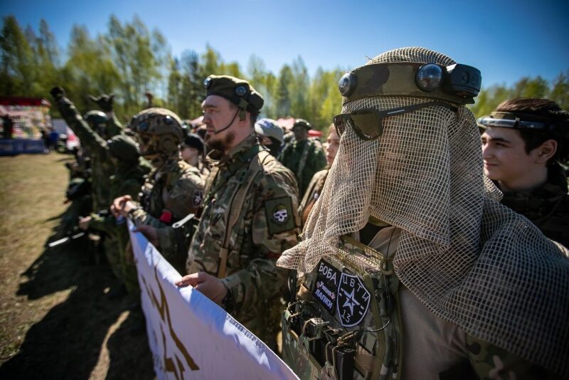 Игроки LASERWAR в камуфляже держат баннер перед зрителями