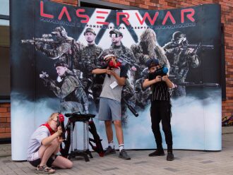 Юные бойцы LASERWAR позируют с оружием на фоне баннера.