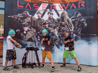 Дети с оружием LASERWAR перед баннером с бойцами.