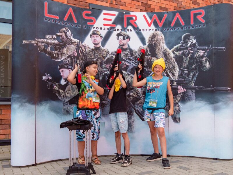 Дети с ярким оружием LASERWAR на фоне баннера.