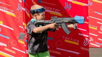 Мальчик с автоматом LASERWAR прицеливается в сторону.