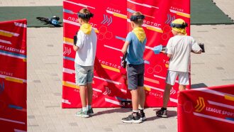 Дети в очках и с оружием LASERWAR у красных баннеров.