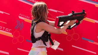 Девочка в жилете LASERWAR целится из футуристического автомата.