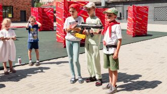 Дети с оружием LASERWAR позируют на фоне ярких баннеров.