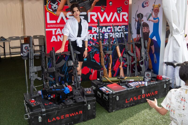 Девушка демонстрирует арсенал LASERWAR на выставке.