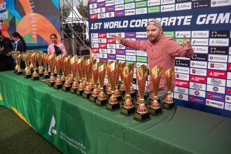 Мужчина с наградами на фоне баннера корпоративных игр.
