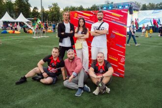 Группа товарищей позирует на фоне яркого баннера LASERWAR.