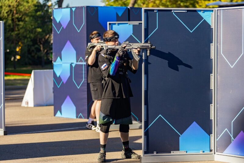 Игрок LASERWAR с оружием наготове за синим укрытием.