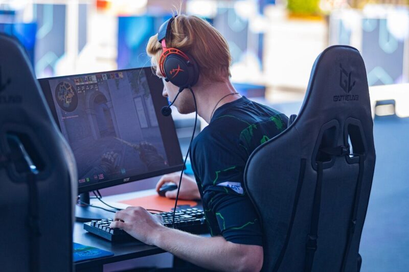 Игрок LASERWAR в наушниках увлеченно управляет игрой на компьютере.