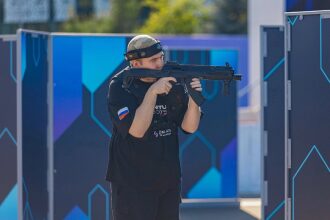 Боец LASERWAR с автоматом за синим игровым укрытием.